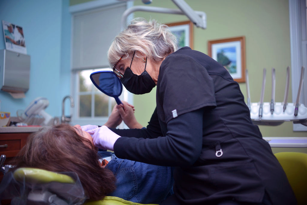 Dental team member helping a patient view her teeth with a mirror at Seven Hills General Dentistry in Bridgetown